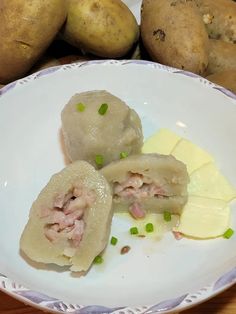 some food is on a white plate with green onions and potatoes in the back ground