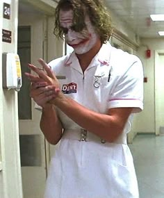 a man dressed as the joker is holding his hands out in front of an open door