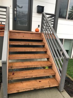 a wooden stair case with metal handrails and an orange pumpkin sitting on top