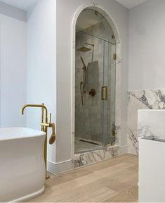 a bathroom with marble and gold fixtures in the bathtub, shower, and sink