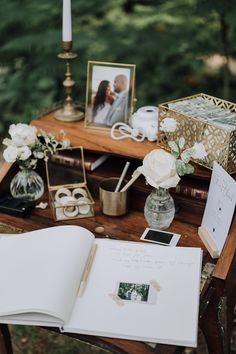 an open book sitting on top of a wooden table next to a vase filled with flowers