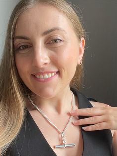 a woman wearing a necklace with a cross pendant on it's neck, smiling at the camera