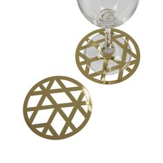 two wine glasses sitting next to each other on top of a white surface with gold geometric designs