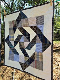 two quilts hanging on clothes pins in the woods with trees and grass behind them