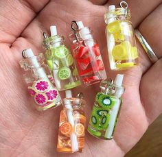 small glass bottles filled with different types of fruit and juice flavored in them on a person's palm