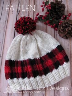 a knitted hat sitting on top of a wooden table next to pine cones and berries