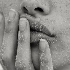 a close up of a person's face with sand on their hands and fingers