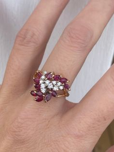 I love the finger coverage with so much sparkle. The shape of the ring flows beautifully on the finger as well.  I can't stop staring at this one. There are 11 very sparkly single cut diamonds measuring 1.5mm each for an approx .17ctw. There are 12 genuine red rubies measuring approx  approx 1.20ctw.  Ring weighs 5.4g and measures 15mm at its widest point for excellent finger coverage. The band tapers down to 2mm at the back of the shank. It is stamped 14k yellow gold. Ring size is 5.25 and sizable.  I can size it for an additional charge. Let me know if you need a quote. Round Cut Diamond Cocktail Ring With Rubies, Diamond Cluster Ruby Ring With Diamond Accents, Ruby Ring With Diamond Cluster And Brilliant Cut, Cluster Ruby Ring With Brilliant Cut Diamonds, Cluster Diamond Ring With Vvs Clarity And Ruby, Ruby Ring With Diamond Accents Fine Jewelry, Dazzling Marquise Diamond Ring With Gemstone, Marquise Ruby Ring With Rose Cut Diamonds, Cluster Ruby Ring With Rose Cut Diamonds