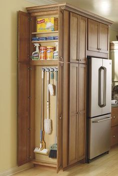 an organized kitchen with wooden cabinets and stainless steel appliances in the corner, along with cleaning supplies