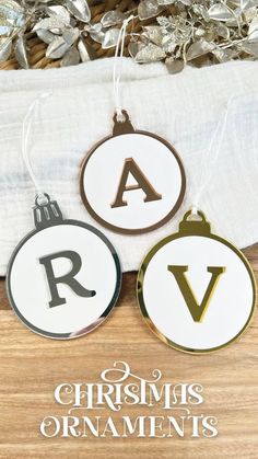 three christmas ornaments with the letter's in gold, white and black on them