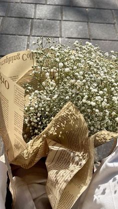 a bouquet of white flowers sitting on top of a newspaper