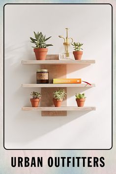 three wooden shelves with plants and books on them in front of a white wall that says urban outfitters