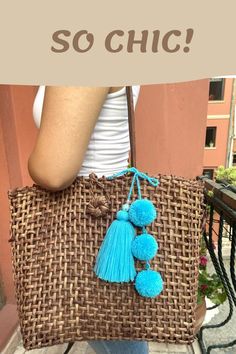 a woman is holding a brown bag with blue pom - poms on it