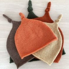 three crocheted bibs on top of each other, one with an orange and the other brown