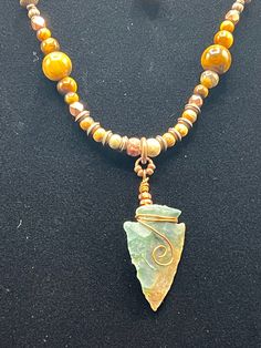 a necklace with a yellow bead and a green pendant hanging from it's side