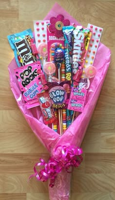 a pink bouquet filled with candy and candies on top of a wooden floor next to a wall