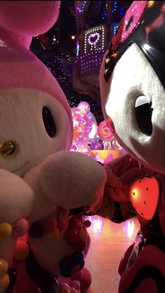 two large stuffed animals standing next to each other in front of a building decorated with lights