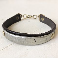 Our mens synergy leather & pewter bar bracelet is a mixed metal jewelry cuff - featuring brass rivets and is great for anyone with an urban or skater style. A rugged, stylish unisex leather strap cuff - that looks great either on it's own, or with other bracelets (as shown in the last 3 images). It's edgy, yet simple and perfect for a day in the city, or a night on the town.The bracelet is made with very dark brown/almost black leather and a pewter bar tag that has been riveted in place. It Rivet Jewelry, Cold Connections, Altered Jewelry, Leather Goodies, Leather Cord Bracelets, Leather Wristbands, Mixed Metal Jewelry, Bar Bracelets, Skater Style