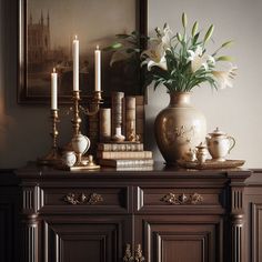 a vase with flowers and candles on top of a dresser