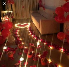 a living room filled with lots of red balloons and streamers on the floor next to a couch