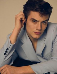 a young man in a blue suit poses for the camera with his hand on his head