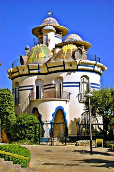 a large white building with blue and yellow designs on it's roof, surrounded by trees