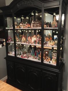 a black china cabinet filled with lots of christmas decorations