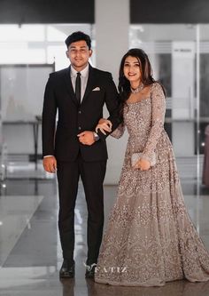 a man and woman standing next to each other in formal wear, posing for the camera