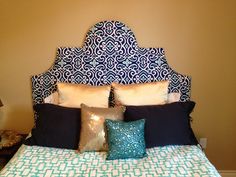 a bed with blue and white pillows on it's headboard in a bedroom