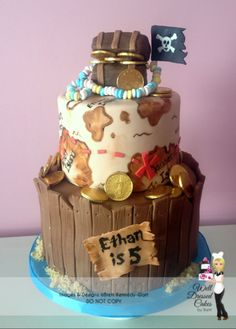 a birthday cake decorated with pirate decorations and gold coins on a blue plate in front of a purple wall