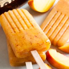 an apple popsicle sitting on top of a white plate next to sliced peaches