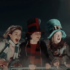 three young women wearing hats and scarves are posing for the camera with their mouths open