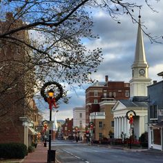 an empty street with christmas decorations on the side and a church steeple in the background