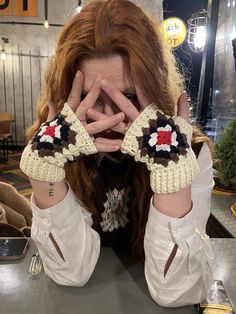 a woman with red hair covering her eyes and holding her hands up in front of her face