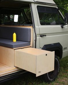 the back end of a van with an empty seat and storage box on it's side