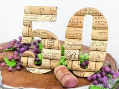 a 50th birthday cake decorated with wine corks and purple berries on a silver platter