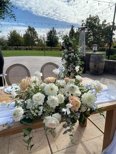 a table with flowers on it in front of some wine barrels and tables cloths