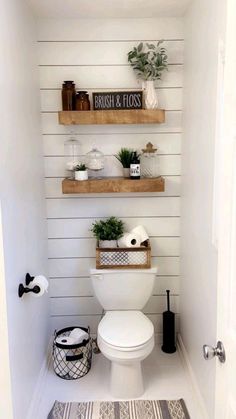 a white toilet sitting in a bathroom next to a shelf filled with plants and other items