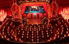 an auditorium filled with lots of lights and chandeliers on the stage in front of it