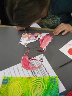 a young boy is painting on paper with watercolors