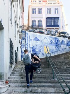 a man walking up some stairs with a baby in a stroller on his back