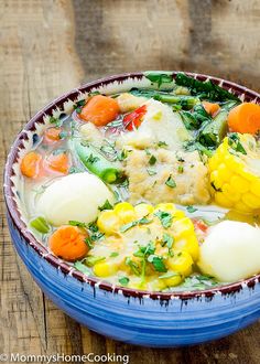 a bowl filled with soup and vegetables on top of a wooden table