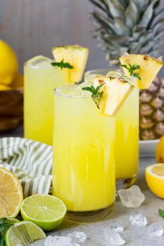 two glasses filled with lemonade and garnish next to sliced pineapples