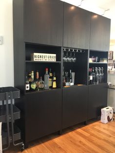 a bar with liquor bottles and glasses on the top shelf in a room that has hardwood floors