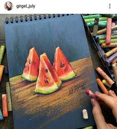 someone is drawing watermelon slices with crayons on the table next to them