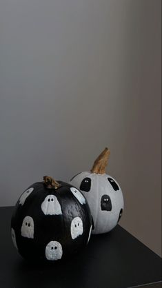 two black and white painted pumpkins sitting on top of a table next to each other