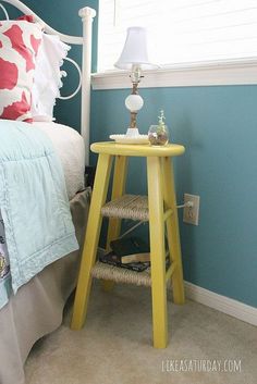 a bedroom with blue walls and a yellow stool in front of the bed that's up against the wall