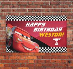 a birthday banner on a brick wall with cars and checkered flags in the background