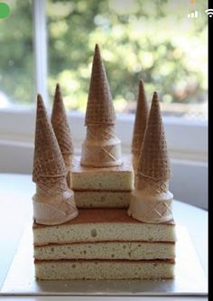 there are four pieces of cake with cones on top of each one, sitting on a table in front of a window