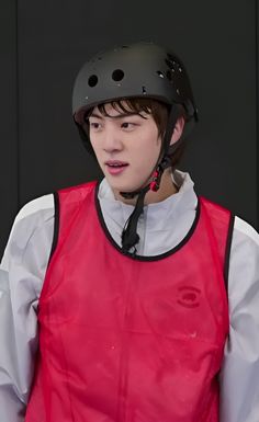 a young man wearing a helmet and red vest